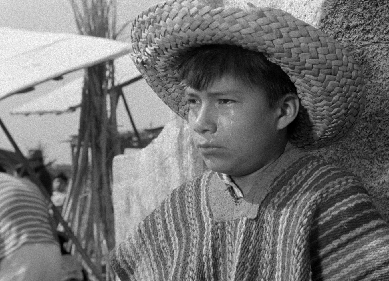 Fotograma de Los olvidados: Pedro, con sombrero de paja, aparece llorando